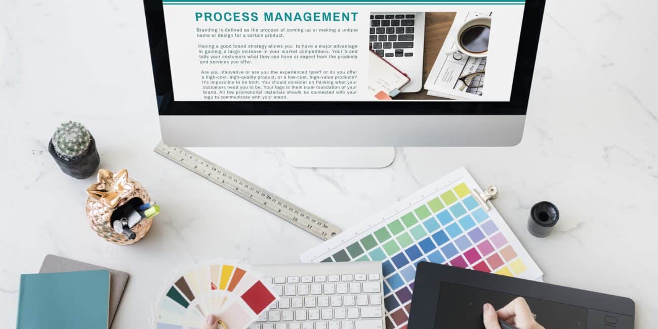 Visual identity system brand materials including color swatches, typography, and logo guidelines on a designer's desk