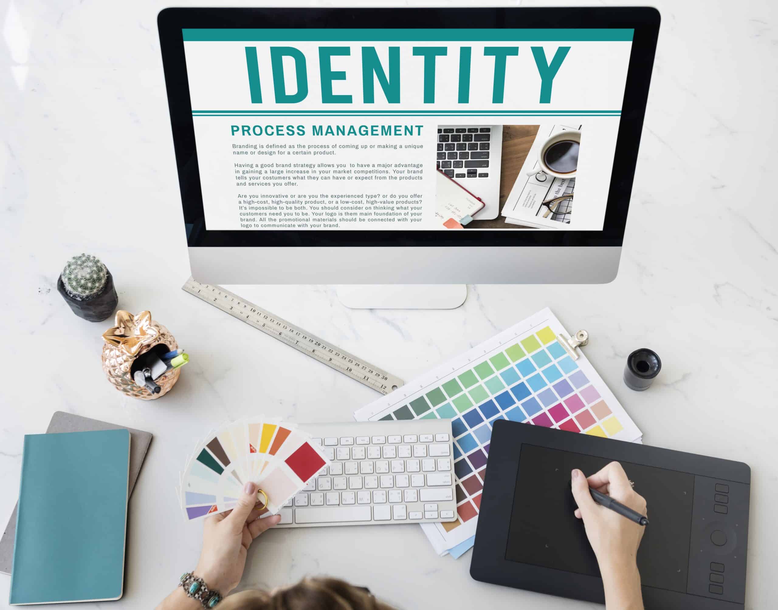 Visual identity system brand materials including color swatches, typography, and logo guidelines on a designer's desk