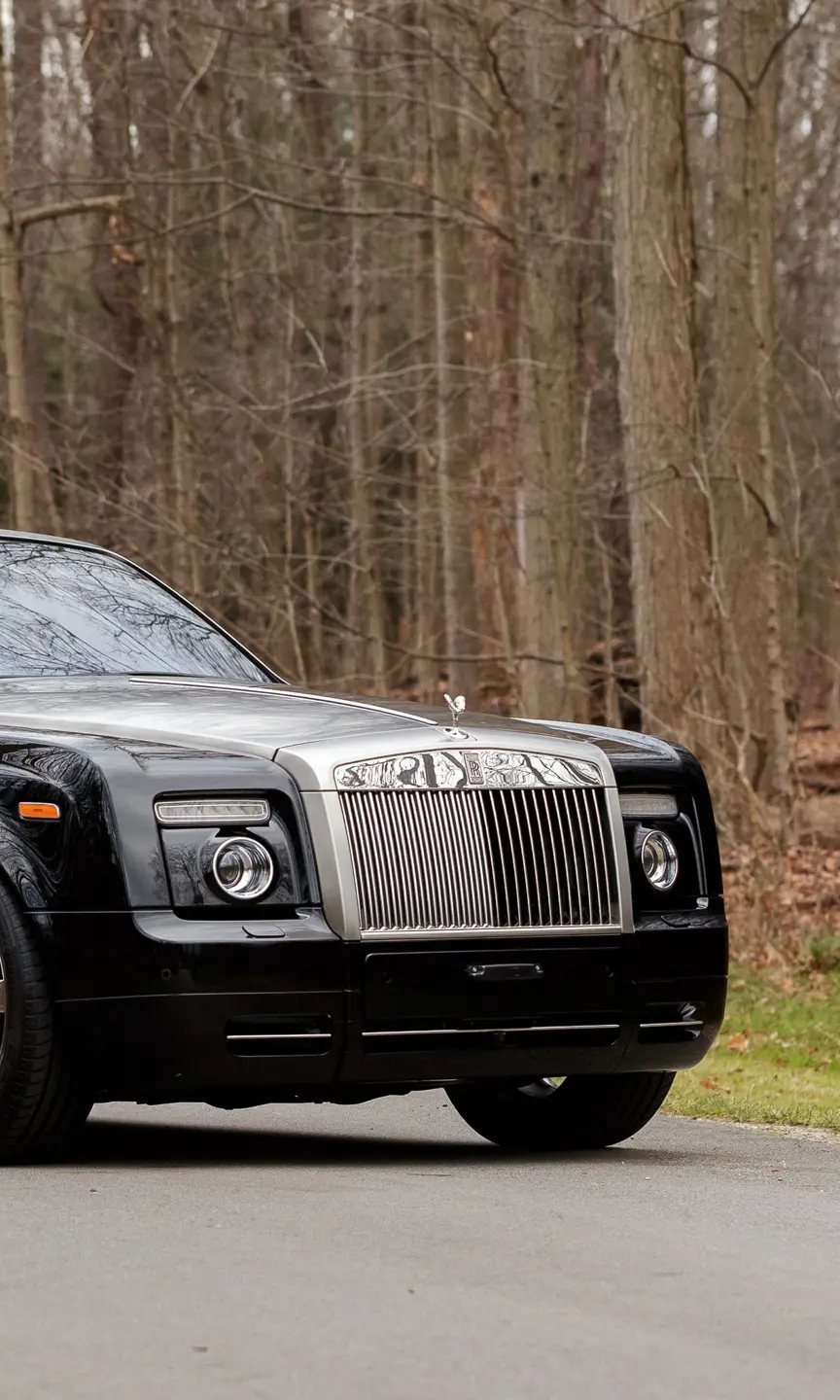 Black Rolls-Royce Drophead on a road through bare woods