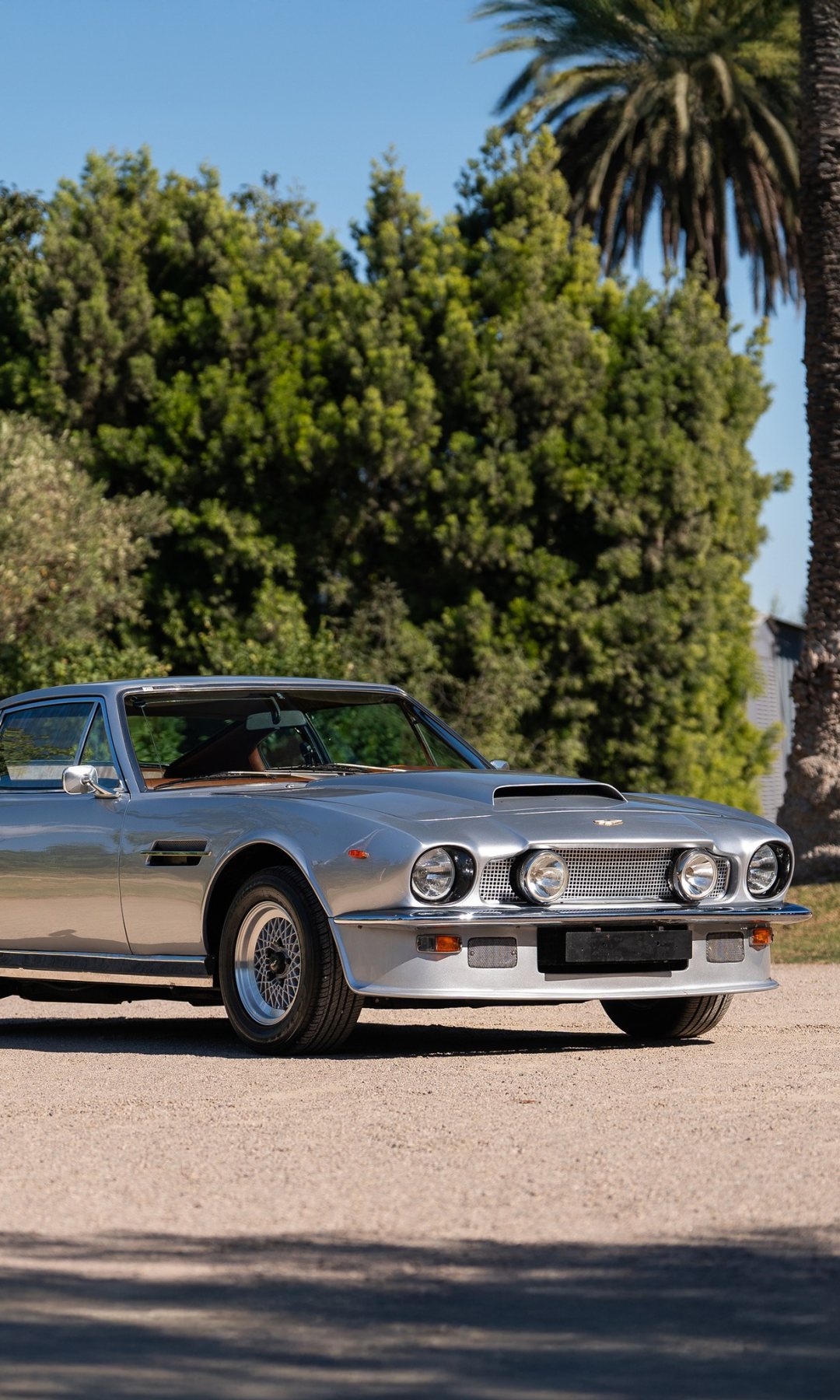 Silver Aston Martin V8 Vantage on a gravel drive in daylight